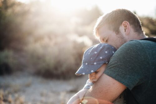 บทความที่ 26 : การรับบุตรบุญธรรมให้เกิดสิทธิและหน้าที่ตามกฎหมาย A father lovingly embraces his baby outdoors on a sunny day. Perfect for Father's Day themes.