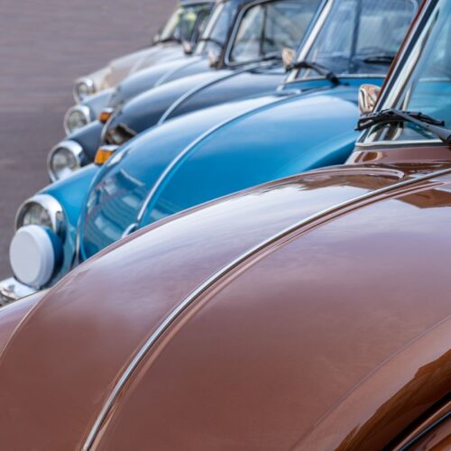 Front view of vintage Volkswagen Beetles aligned perfectly outdoors.