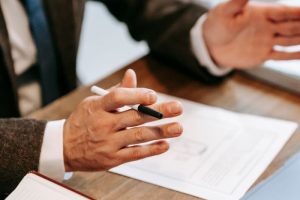 Professional discussing documents over a wooden table in an office setting.